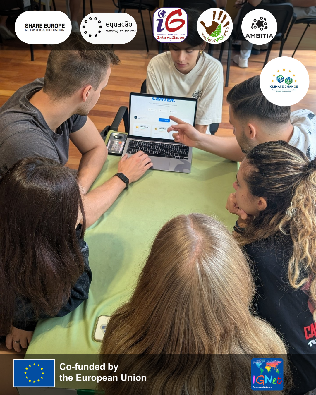 gruppo di sei partecipanti impegnati in un’attività collaborativa attorno a un tavolo, mentre discutono e lavorano su un progetto al computer.