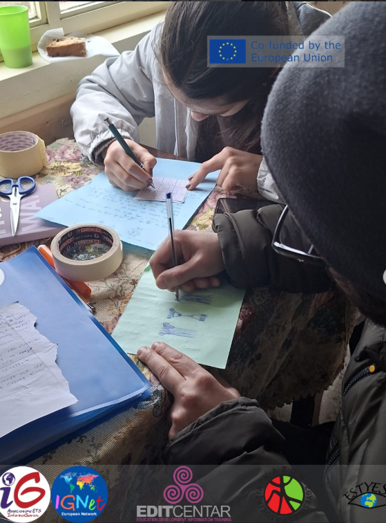 Due giovani partecipanti scrivono e disegnano su fogli colorati durante un'attività laboratoriale, in un progetto cofinanziato dall'Unione Europea