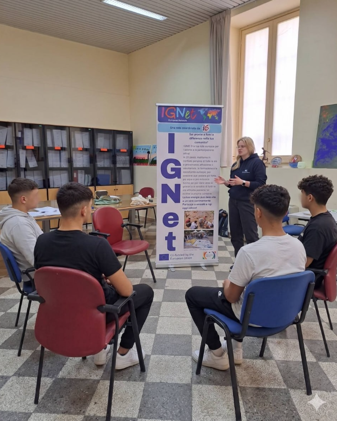 Una volontaria presenta le opportunità europee a un gruppo di giovani dell'USSM di Palermo, accanto al roll-up della rete IGNet cofinanziata dall'Unione Europea