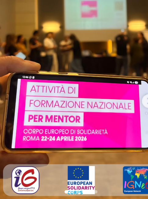 Uno smartphone in primo piano mostra la locandina dell'attività di formazione nazionale per mentor del Corpo Europeo di Solidarietà, svoltasi a Roma dal 22 al 24 aprile 2026; sullo sfondo, i partecipanti al lavoro in sala durante il training.