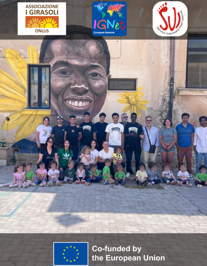 Il gruppo che ha reso possibile il murale giovani, volontari, operatori e bambini della scuola in posa nel cortile del complesso scolastico 