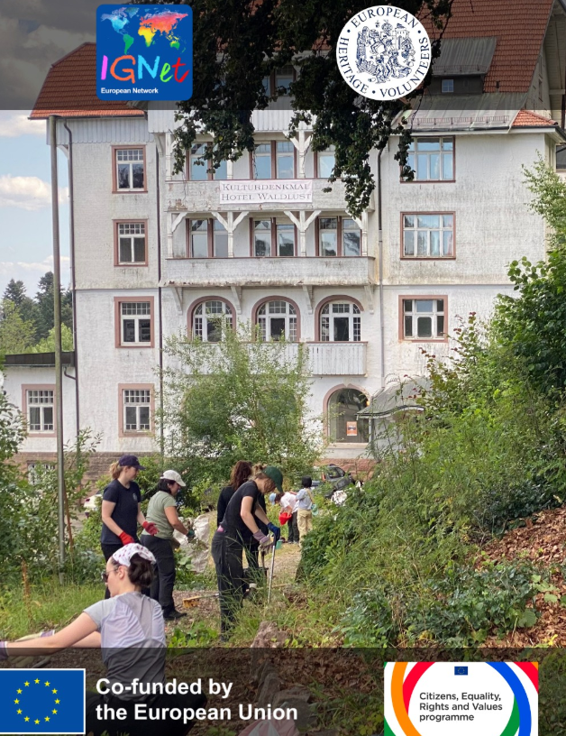gruppo di volontari impegnati in attività di cura del paesaggio nel parco storico che circonda l’ex Grand Hotel Waldlust. Sono circondati da vegetazione e attrezzi da lavoro, mentre sullo sfondo si vede l’edificio storico, caratterizzato da più piani, grandi finestre ad arco e un’architettura tipica delle strutture termali di fine Ottocento.