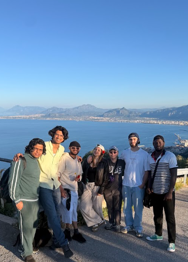 gruppo di sette partecipanti in piedi su una terrazza panoramica, affacciata su un ampio tratto di mare e sulla città costiera alle loro spalle.